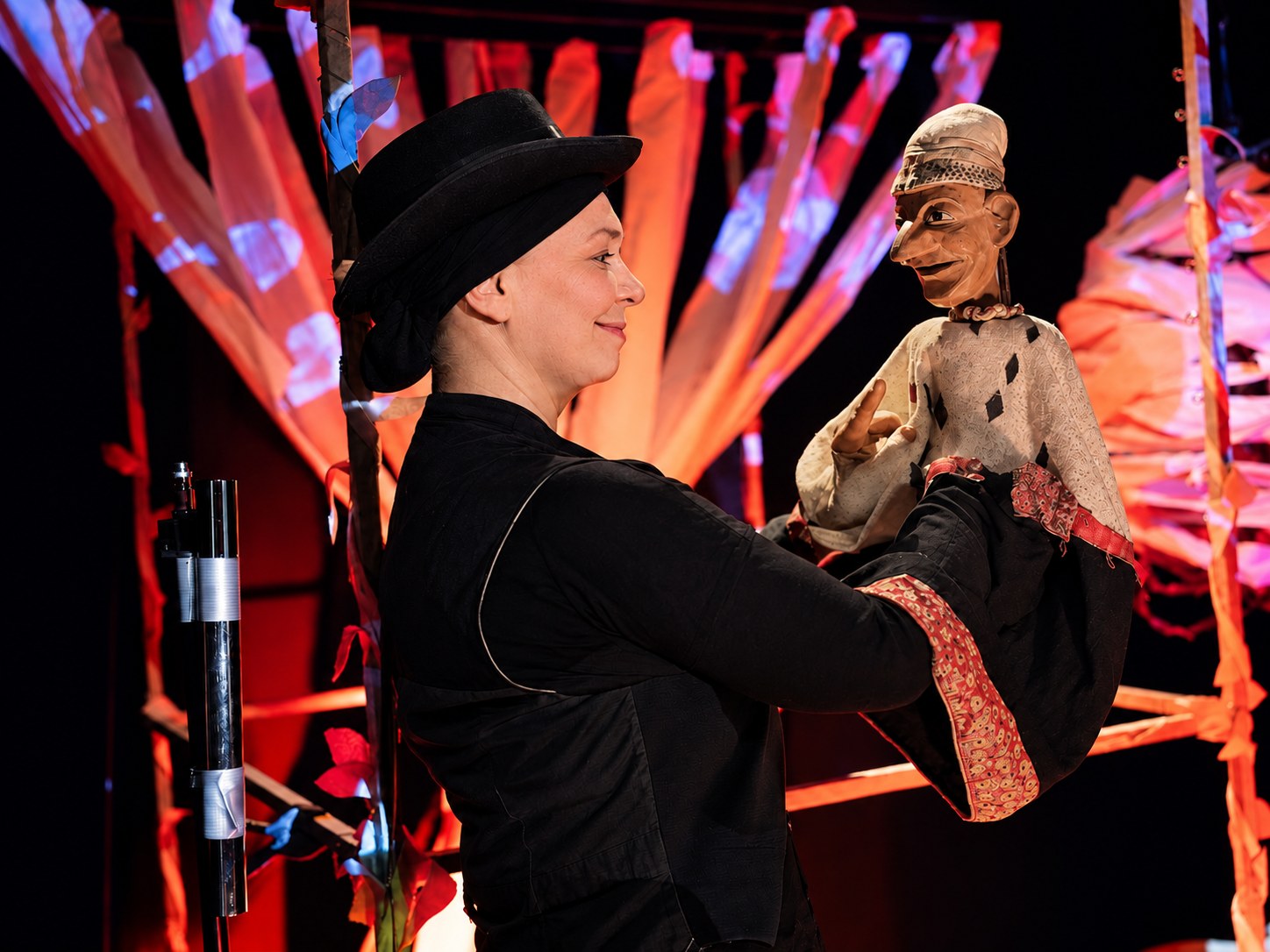 Puppenspielerin und Kasper vor der farbigen Waldszenen-Kulisse